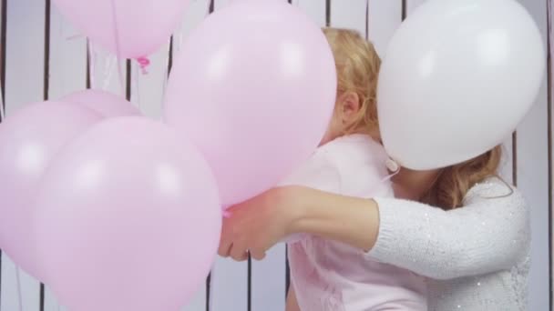 Bebê menina e seu moter brincando com balões de brinquedo rosa e branco em câmera lenta — Vídeo de Stock