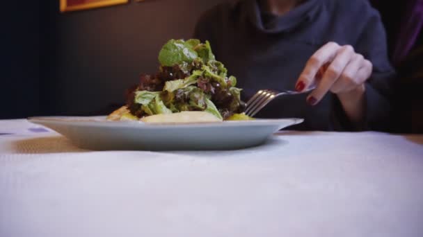 Женщина использует вилку и нож, чтобы съесть зеленый салат — стоковое видео