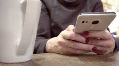 Kadın Kupası ile telefonunu elinde tutar.