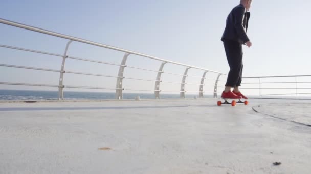 Giovane in scarpe da ginnastica rosse pattinaggio al mare — Video Stock