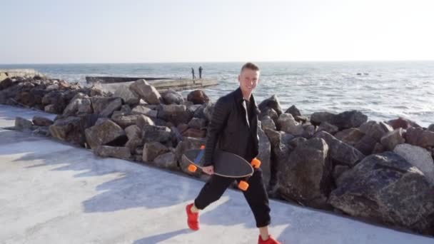 Jovem caminha com o seu longboard junto ao mar — Vídeo de Stock