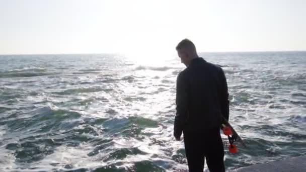 Jeune homme tient son longboard debout au bord de la mer — Video