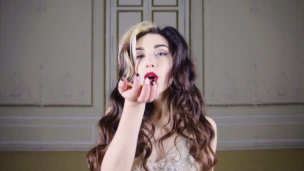 年轻的黑发女人，用红红的嘴唇吹金五彩纸屑 — 图库视频影像