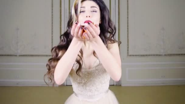 Young brunette woman with red lips blows gold confetti — Stock Video