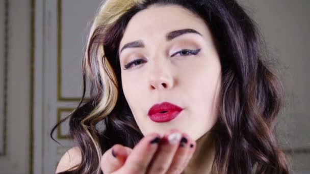 Young brunette woman with red lips blows gold confetti — Stock Video