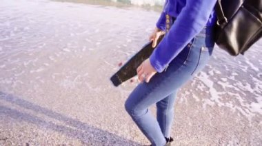 Uzun saçlı sarışın kadın deniz kaymak ile yürüyor