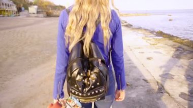 Genç güzel kız onun paten kurulu ile deniz kenarında yürüyor.