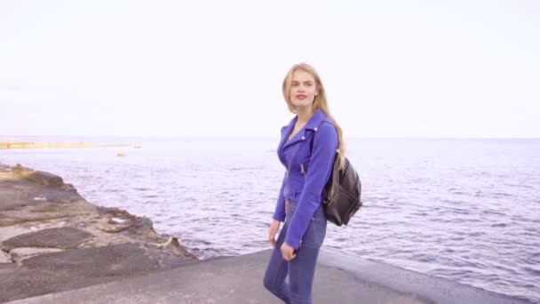 Молодая красивая девушка стоит со своей скейт-борд у моря — стоковое видео