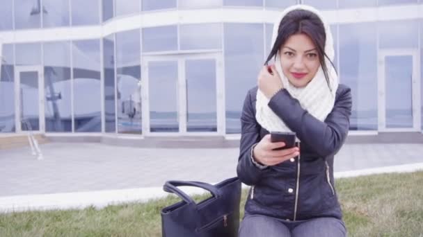 Telefonuyla ilgili dışında genç esmer kadın oturur — Stok video