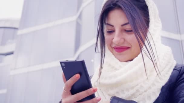 Junge brünette Frau sitzt draußen mit ihrem Handy — Stockvideo