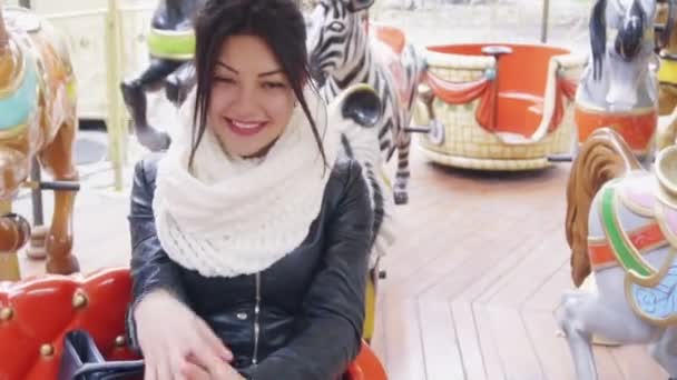 Mooie brunette meisje paardrijden op carrousel — Stockvideo