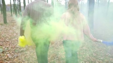 Erkek ve kadın yürümek ormanda parlak sarı ve mor duman.