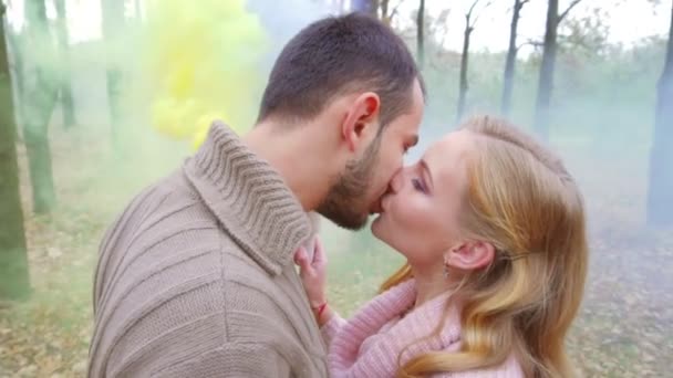 Hombre y mujer besándose y sosteniendo humo amarillo brillante y púrpura. En el bosque — Vídeos de Stock