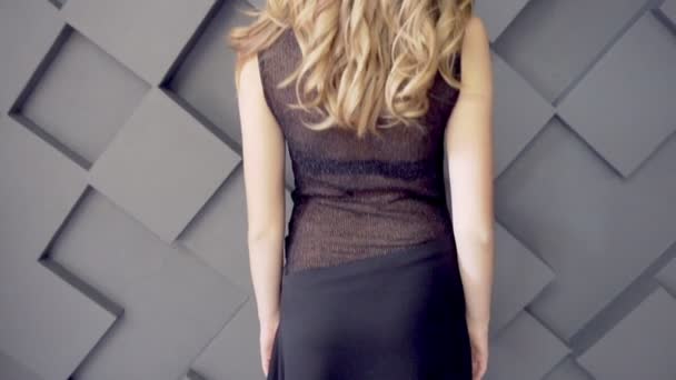 Beautiful girl in a long dress turns out to back on a dark background — Stock Video