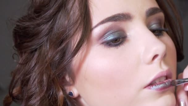 Kadeřnice dělá make-up krásná žena ve studiu s vlnitý účes — Stock video