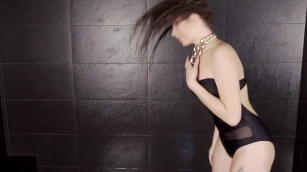 Jeune femme mince sexy secouant la tête, prenant une douche et debout près du mur carrelé — Video