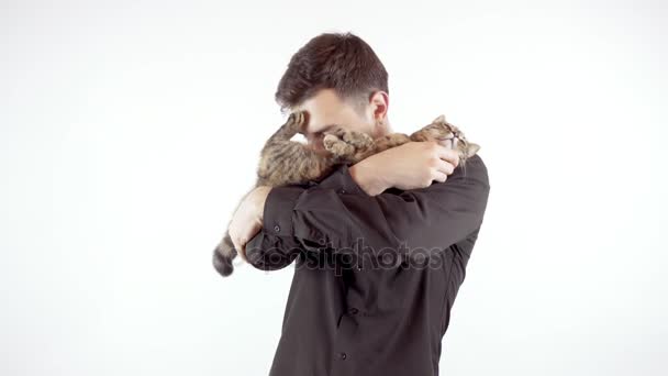 Joven hombre guapo sosteniendo y abrazando a su gato aislado sobre fondo blanco — Vídeos de Stock