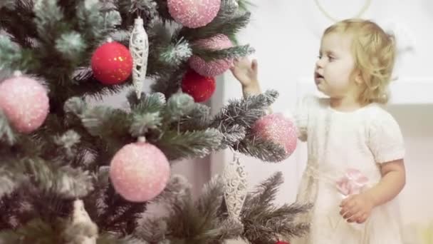 Pequeña rubia linda chica está jugando con el árbol de Navidad — Vídeos de Stock