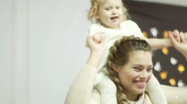 Genç anne onun küçük kızı ile oynuyor. Küçük şirin bebek kız onun anneler omuzlarında oturur