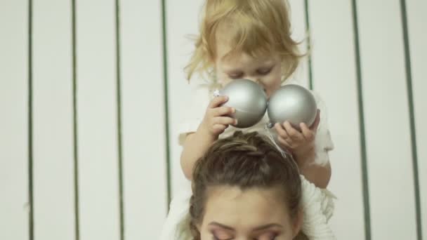 Young mother is playing with her little daugther. Little cute baby girl sits on her mothers shoulders — Stock Video