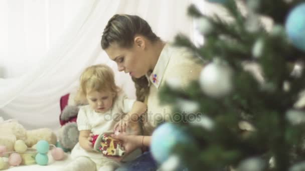 Ung mamma leker med sin baby flicka under granen. Semesterperioden. Tid för familjen. — Stockvideo