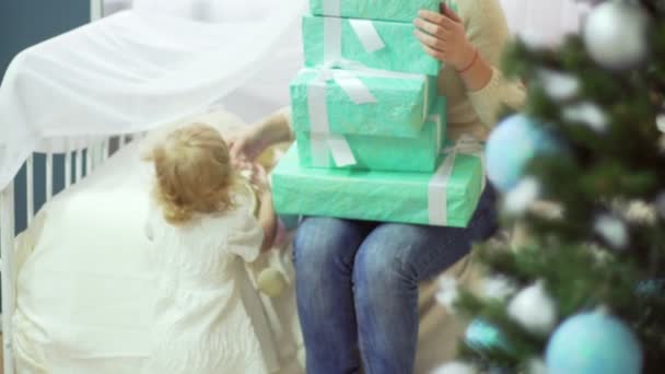 Feliz joven madre con su dulce bebé sosteniendo cajas decoradas con regalos — Vídeo de stock