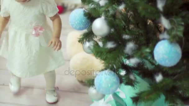 Doux bébé fille prend son cadeau sous le tre de Noël et va à sa jeune mère — Video