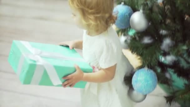 Doux bébé fille prend son cadeau sous le tre de Noël et va à sa jeune mère — Video