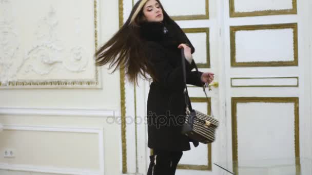 Beautiful young model woman in her black coat takes her keys and bag and goes out — Stock Video