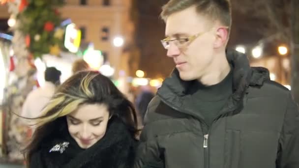 Jong stel lopen togerher in de buurt van kerstverlichting bij kerstmarkt — Stockvideo