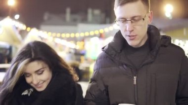 Genç çift togerher Noel ışıkları yakın Noel pazarında bir fincan sıcak çay ile yürümek
