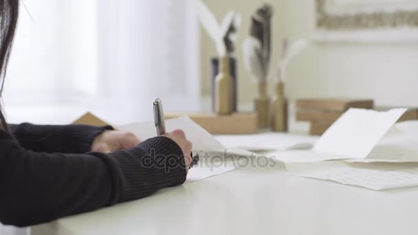 Дівчина з красивими руками пише листа за столом — стокове відео