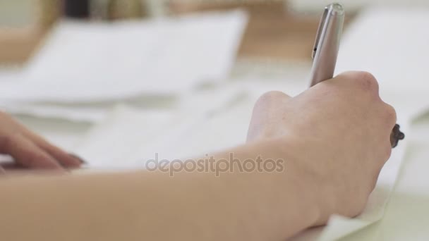 Девушка с красивыми руками пишет письмо за столом — стоковое видео
