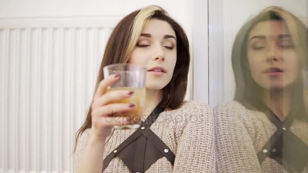 Jolie jeune femme brune boit au verre près de la fenêtre — Video