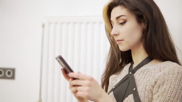 Junge Frau schreibt SMS mit ihrem Freund und lächelt — Stockvideo