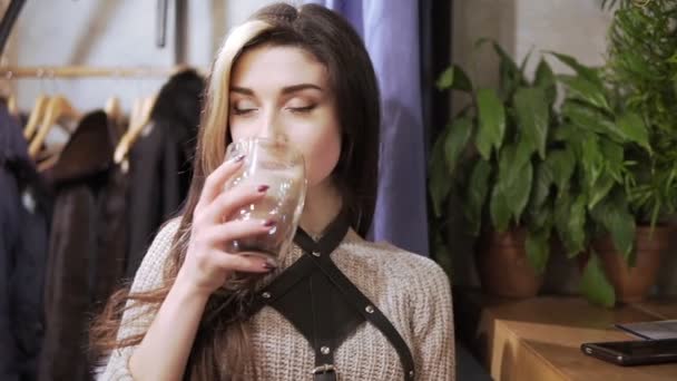 Beautiful Girl Drinking Cacao or Coffee in Cafe. Beauty Model Woman with the Cup of Hot Beverage. Spruces branches at the background — Stock Video