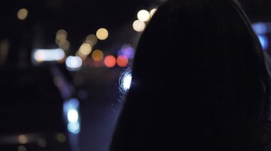 Genç esmer kadın sokakta geceleri durumda. Arka plan şehir trafik