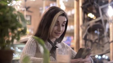 Cafe city yaşam tarzı kadın içme kahve ve akıllı telefon app trendy kentsel kafede kapalı oturan manifatura telefon.