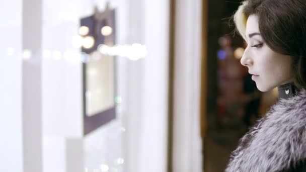 冬の服装の女性は、高価なブティック店のウィンドウのディスプレイの前に立っています。焦点に来る — ストック動画
