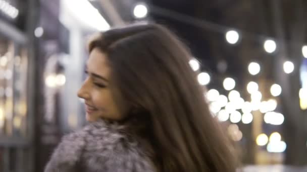 Young beautiful pretty woman smiling at city street in the night against evening lights — Stock Video