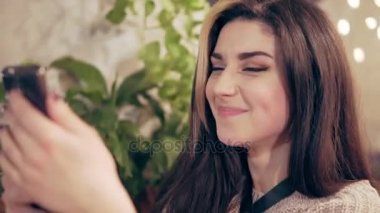 Okuma koşum cep telefonuyla kafede genç esmer kadın iletilerini, gülümsüyor ve cevap başlar