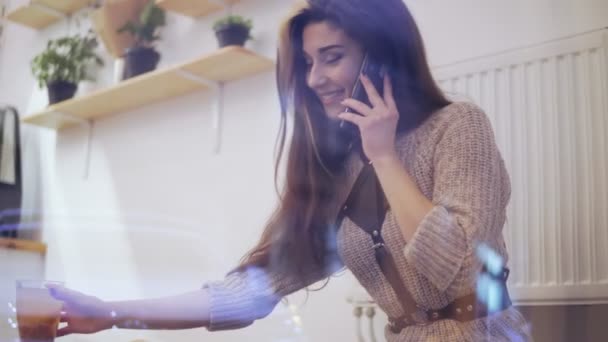 Młoda brunetka kobieta oglądane przez okno rozmowy telefonicznej, uśmiechając się i picie herbaty — Wideo stockowe