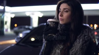 Genç güzel esmer kadın ceket içecekler sıcak içecek araba kukuleta oturan