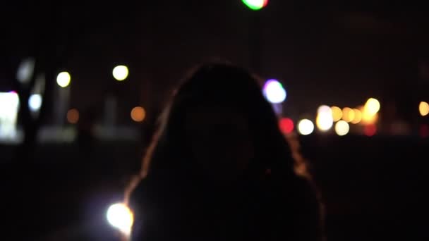 Jeune fille brune dans la rue nuit ville vient à la voiture. Feux de circulation dans les coulisses .