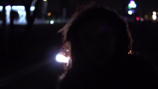 Chica de pie en la calle junto al coche por la noche y agitando la cabeza . — Vídeos de Stock