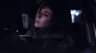 Kış geceleri araba ve içecekler sıcak içecek montlu genç güzel bir esmer kadın oturur