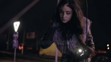 Uzun saçlı genç esmer kadın onun smartphone bir el feneri olarak kullanarak başlık altında arıyor