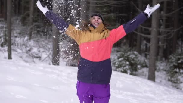 Зимний пейзаж красивый снегопад счастливая женщина играет с падающим снегом. Молодая девушка развлекается игриво бросая снег играя на улице с руками вверх в воздухе игривый в зимнее время . — стоковое видео