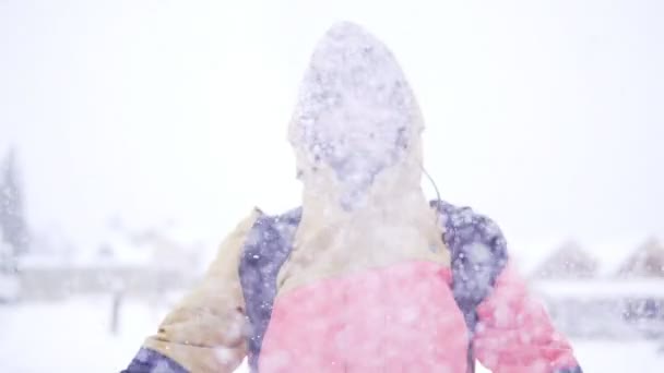 Jeune fille en vêtements d'hiver lumineux s'amuser en plein air dans la forêt d'hiver sous les flocons de neige . — Video