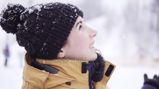 Lachende jonge vrouw in bobbel hoed opzoeken en genieten van de sneeuw — Stockvideo